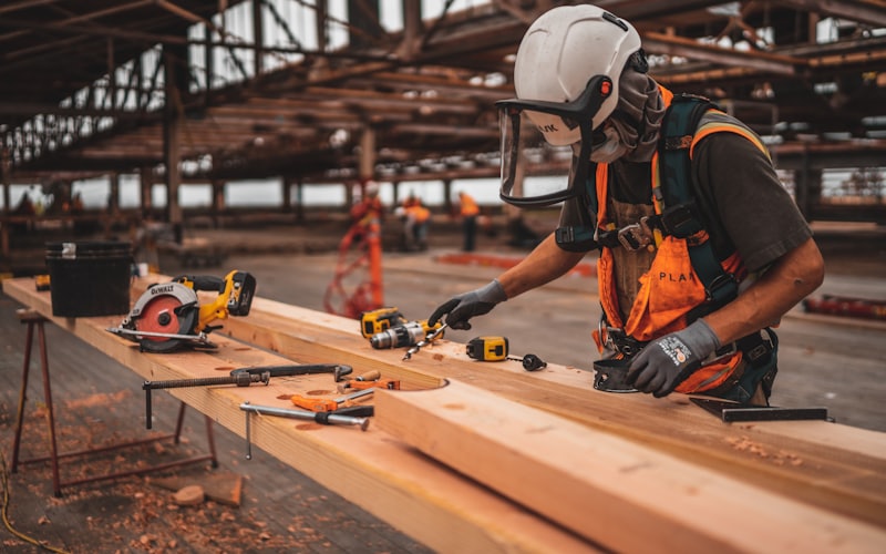 Site worker in a safety helmet and high visibility workwear using a power tool