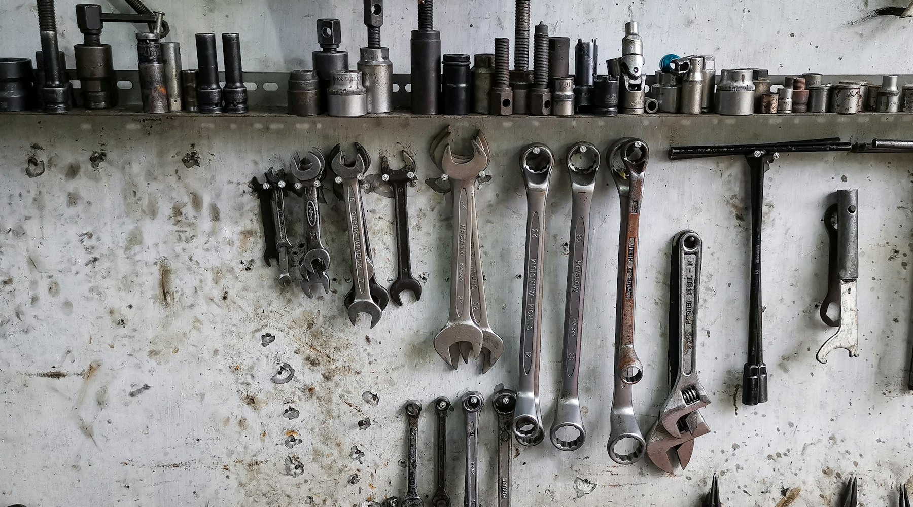 Spanners and socket sets lined up along an industrial workshop wall