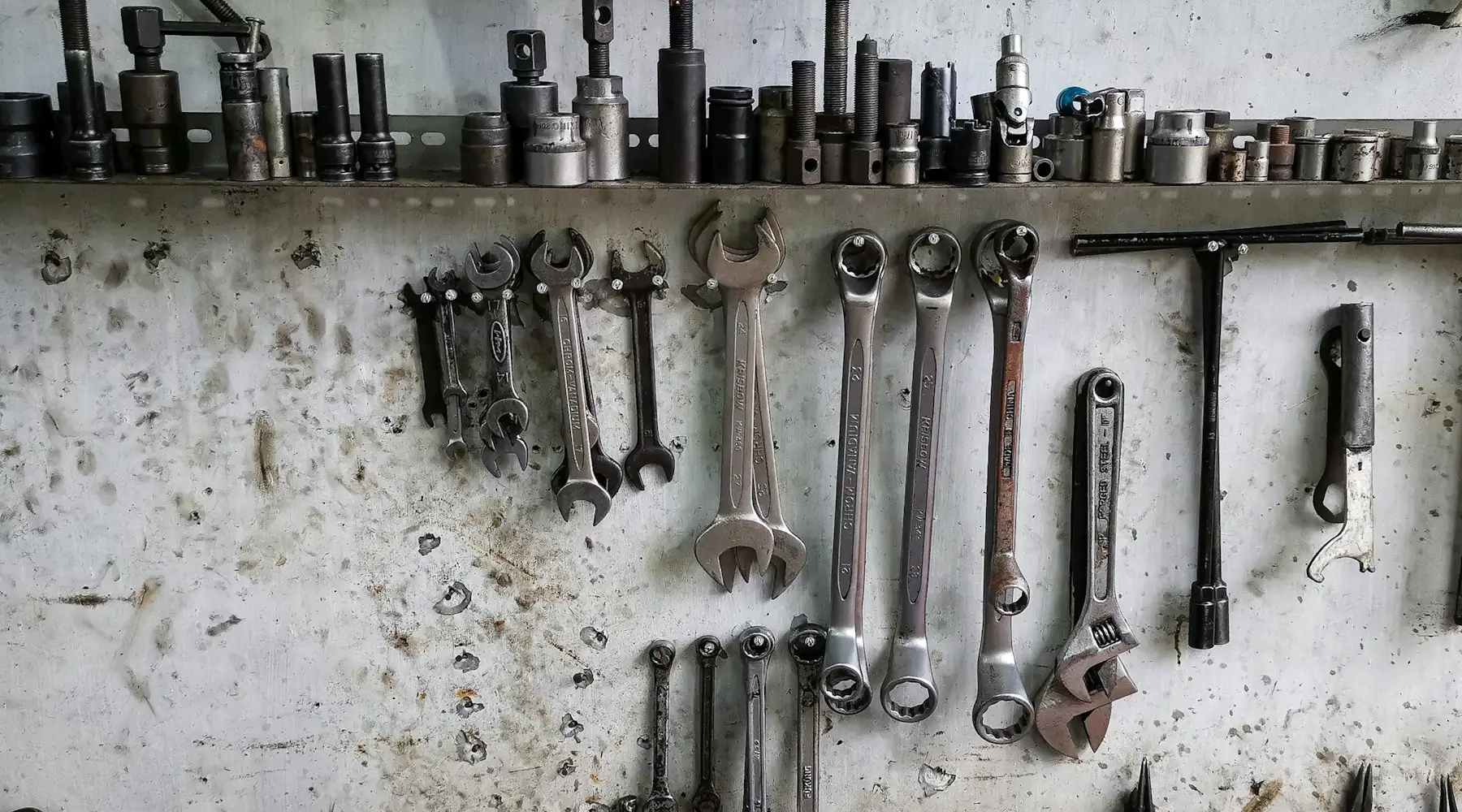 Spanners and socket sets lined up along an industrial workshop wall